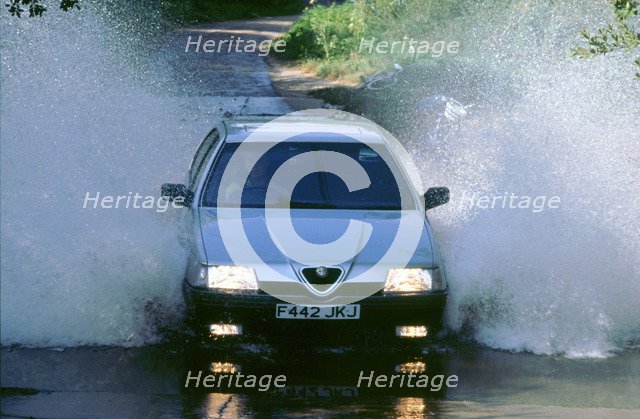 1989 Alfa Romeo 164 driving through a ford. Artist: Unknown.