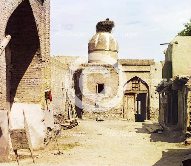 View of a courtyard, adobe buildings, and a bird's nest atop a dome, between 1905 and 1915. Creator: Sergey Mikhaylovich Prokudin-Gorsky.