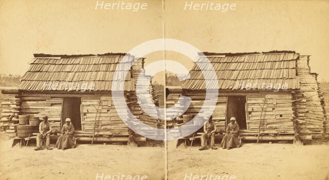 Uncle Ben's cabin, [Elderly couple sitting in front of a cabin], (1868-1900?). Creator: Unknown.