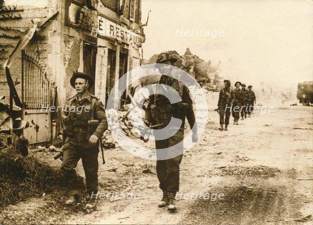 British troops walk through the village of Douet, after the fall of Bayeux, June 1944. Artist: Unknown