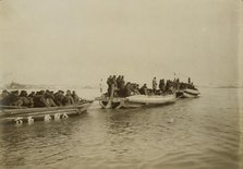 Steam launch carrying six over-crowded boat loads soldiers to landing, Chemulpo, c1904. Creator: Robert Lee Dunn.