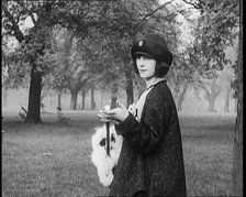 Female Civilian Dressed Glamorously Holding a Fur Trimmed Parasol in a Park, 1920. Creator: British Pathe Ltd.