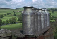 Milk cans at farm gateway.