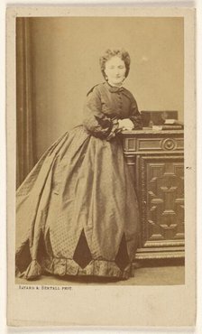 Unidentified woman standing, leaning against a credenza, about 1861. Creator: Bayard & Bertall.