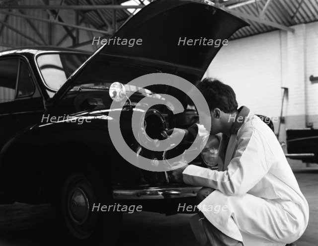 Auto electrician changing a light bulb on a Morris Minor, Nottingham, Nottinghamshire, 1961.  Artist: Michael Walters