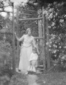 Conroy, Frank, Mrs., and child, standing by a garden gate, 1923 Creator: Arnold Genthe.