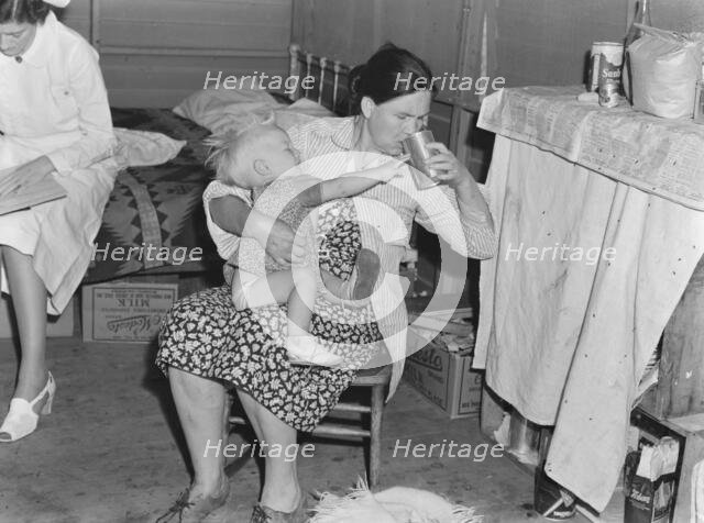 Mother from Oklahoma tends baby with dysentery, FSA camp, Tulare County, California, 1939. Creator: Dorothea Lange.