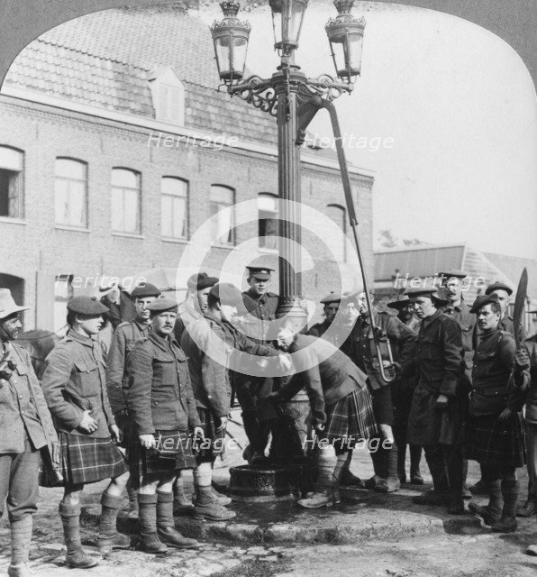 Soldiers filling their water bottles at the town pump La Gorgue, France, World War I, c1914-c1918. Artist: Realistic Travels Publishers