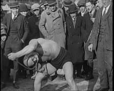 A Strongman Bending an Iron Bar Around His Head, 1921. Creator: British Pathe Ltd.