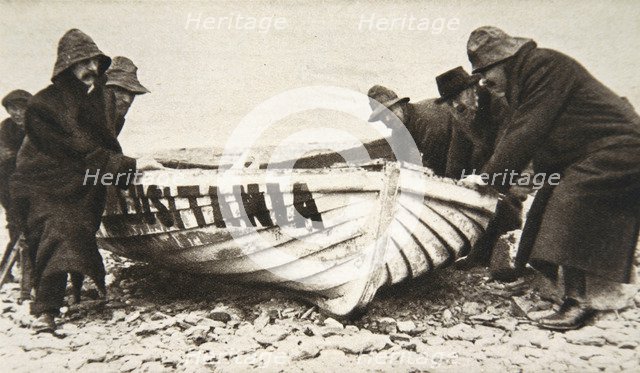 Hauling one of the 'Lusitania's' lifeboats onto the beach, Ireland, 8 May 1915.  Artist: Clarke & Hyde