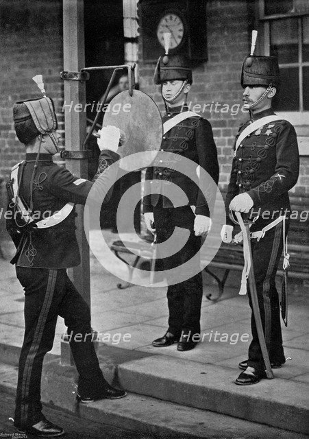 Striking the gong at the main gate of the Aldershot cavalry barracks, Hampshire, 1896. Artist: Gregory & Co
