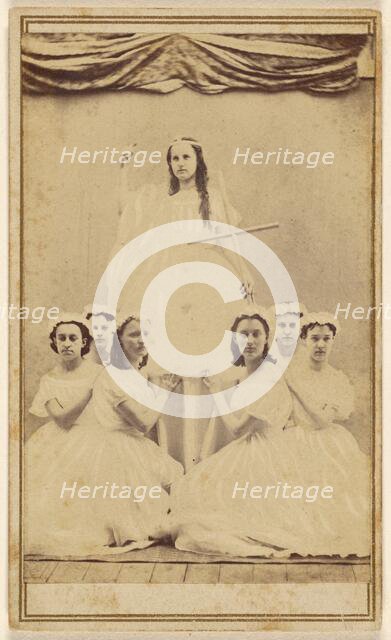 Female group portrait, six in white gowns kneeling, one standing holding a cross, about 1865. Creator: Unknown.