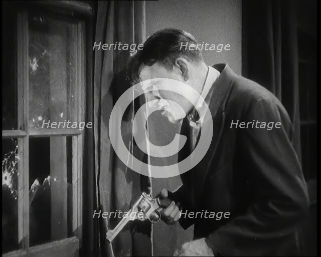 Scene from the Film 'The Informer':  Male Actor Shooting a Gun Out of a Window, 1920s. Creator: British Pathe Ltd.