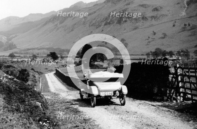 A vintage car travelling along a lane through the Lake District, Cumbria, 1920s. Artist: Unknown