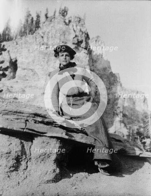 Frances Benjamin Johnston, full-length portrait, seated on rock in Yellowstone National Park, 1903. Creator: Frances Benjamin Johnston.