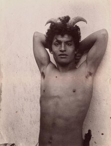 A Sicilian boy naked from the waist up, his hands behind his head, wearing horns, 3 Feb 1899. Creator: Count Wilhelm von Gloeden.