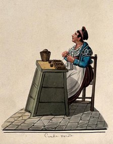 A women is sitting knitting at a table in the street with money on it in trays. Creator: Unknown.