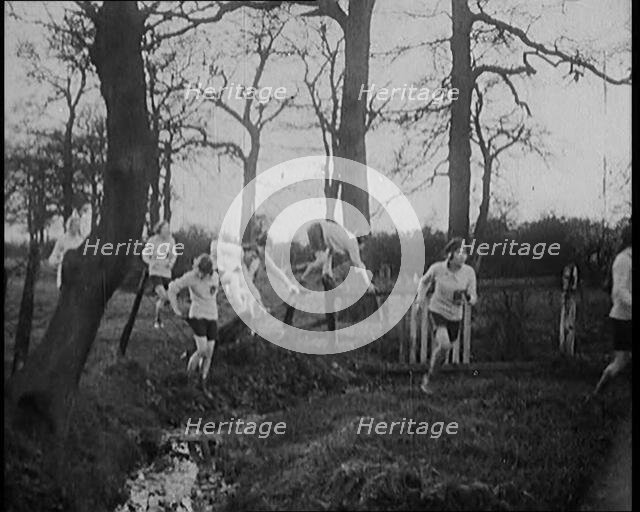 Young Female Civilians Wearing Sport Outfits Running Across a Field Jumping over Water in a..., 1920 Creator: British Pathe Ltd.