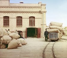 Labourers loading sacks onto railway at factory warehouse, between 1905 and 1915. Creator: Sergey Mikhaylovich Prokudin-Gorsky.