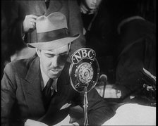A Male American Civilian in a Press Room Speaking at a Microphone That Has the Words NBC..., 1930s. Creator: British Pathe Ltd.