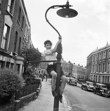 Boy climbing a lamppost, Kentish Town, London, 1960-1965. Artist: John Gay