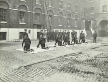 Demonstrating how to pick up an unconscious person, London Fire Brigade Headquarters, London, 1910. Artist: Unknown.