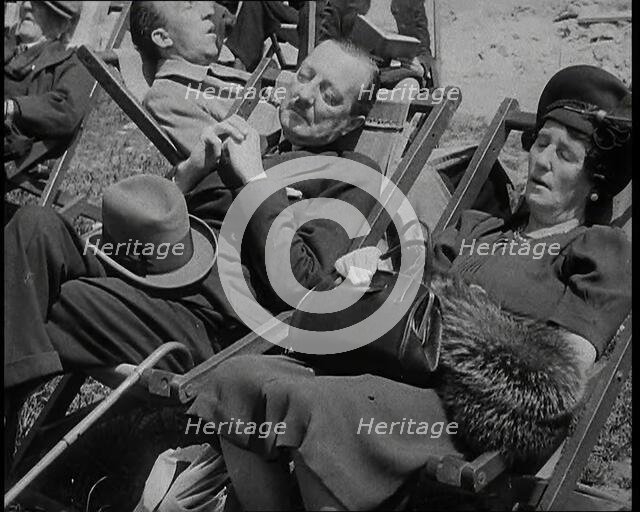 A British Couple Asleep in Deckchairs in the Sunshine in Hyde Park, the Man Has His Legs.., 1938. Creator: British Pathe Ltd.