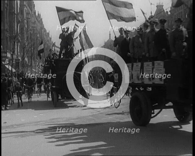 Male Civilians Driven in Trucks Parade Waving Flags. Other Male Civilians Ride Alongside on..., 1924 Creator: British Pathe Ltd.