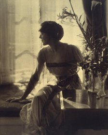 Woman sitting on window seat, looking left, full-length portrait, between 1900 and 1920. Creator: Unknown.
