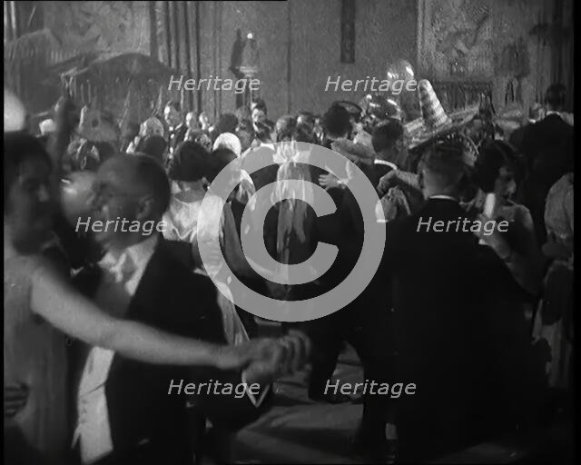 A Crowd of People Dancing at a Fancy Dress Party Whilst a Band is Playing on the Stage, 1920s. Creator: British Pathe Ltd.