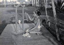 Sarawak: a girl extracting the seeds of raw cotton in a cotton gin, c1900. Creator: Unknown.