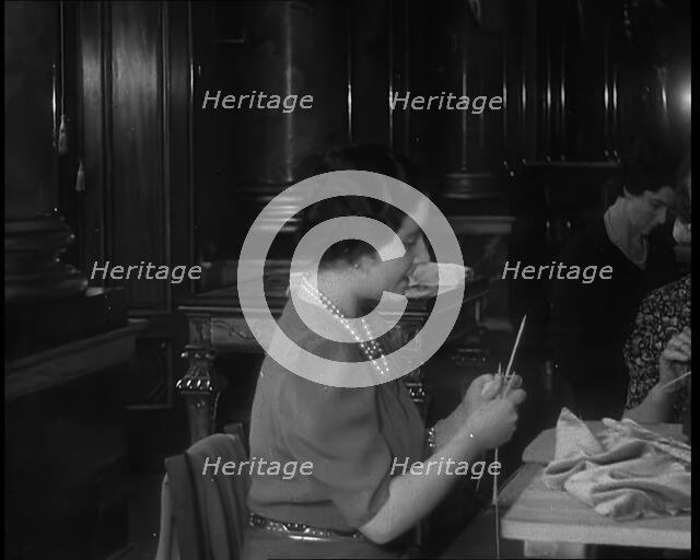 Queen Elizabeth Knitting at a Large Sewing Group Hosted in Buckingham Palace, 1940. Creator: British Pathe Ltd.