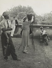 Photographer Frances Benjamin Johnston standing beside her view camera preparing to take..., 1938. Creator: Unknown.