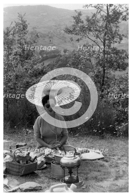 Woman under a parasol having a picnic, c1950-1969(?). Artist: Unknown