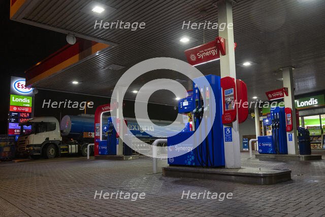 Esso petrol station forecourt with tanker delivering fuel, 2020. Creator: Tim Woodcock.