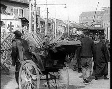 A Male Chinese Civilian Pulling Rickshaws Through the Streets of Shanghai Past Barricades, 1920s. Creator: British Pathe Ltd.