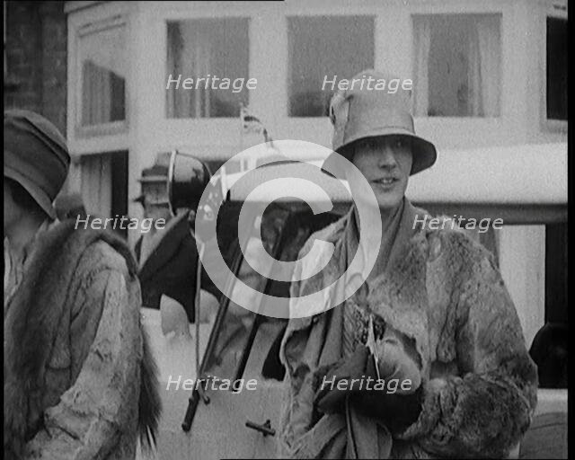 Two Female Civilians Wearing Heavy Coats and Hats Standing in Front of a Car, 1920. Creator: British Pathe Ltd.