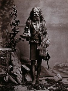 An Indian man wearing many beads, and carrying a begging bowl and an umbrella, in a..., c1900. Creator: Unknown.