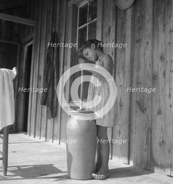 Pottery butter churn on porch of Negro tenant family, Randolph County, N Carolina, 1939. Creator: Dorothea Lange.