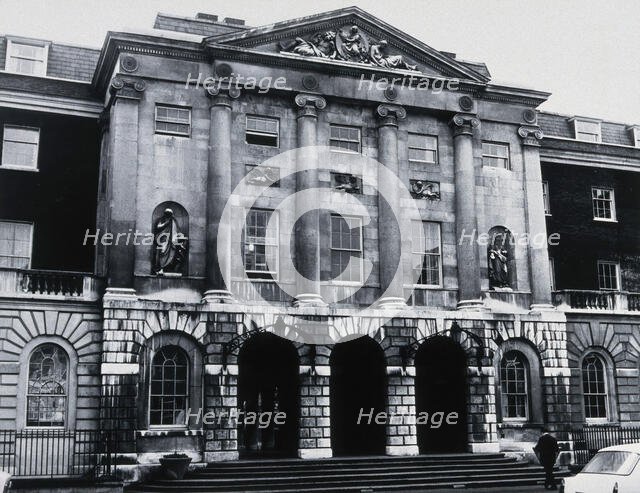 The front entrance of Guy's Hospital, with statues of Aesculapius and Hygieia above the arches. Creator: Unknown.