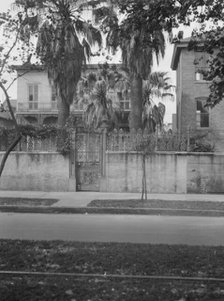 View from across street of two-story house behind wall, New Orleans, between 1920 and 1926. Creator: Arnold Genthe.
