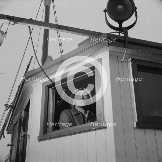 Gloucester, Massachusetts. Lorenzo Scola maneuvers ship during mackerel chase, 1943. Creator: Gordon Parks.