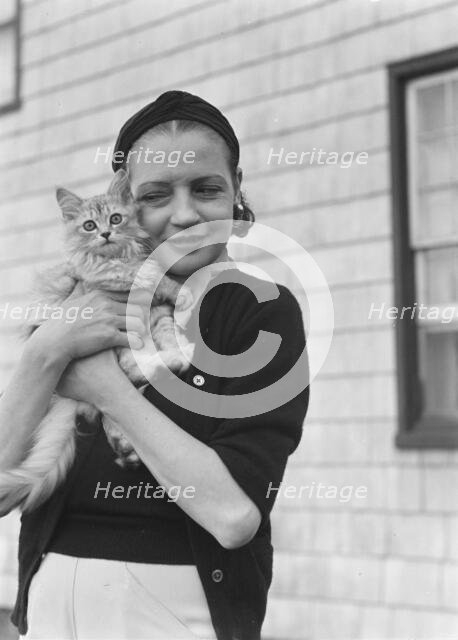 Leonard, Mrs., with cat, standing outdoors, between 1926 and 1938. Creator: Arnold Genthe.