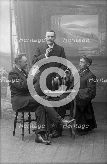 Three men having a beer, posed in a photographer's studio, Landskrona, Sweden, 1910. Artist: Unknown