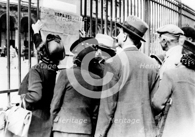 Refugees studying a train timetable, Gare de l'Est, Paris, July 1940. Artist: Unknown