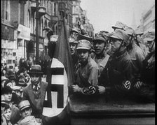 German Civilians and Men in Nazi Uniforms With a Nazi Flag, 1933. Creator: British Pathe Ltd.