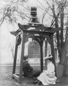 U.S. Naval Academy, Annapolis, Md. 1902?: midshipman and girl sitting beneath bell, (1902?). Creator: Frances Benjamin Johnston.