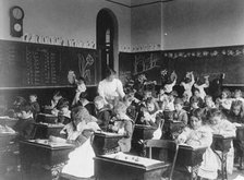 Children modeling clay at desks and drawing on blackboard in Washington, D.C. classroom, (1899?). Creator: Frances Benjamin Johnston.