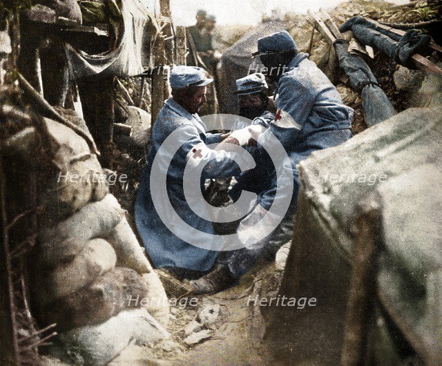 'First aid to a wounded man in one of the French trenches', 1915. Artist: Unknown.