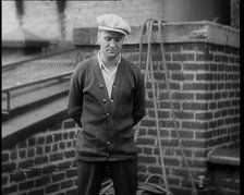 Male Civilian Wearing a Cardigan and a Flatcap Standing in Front of a Wall Talking at the..., 1930. Creator: British Pathe Ltd.